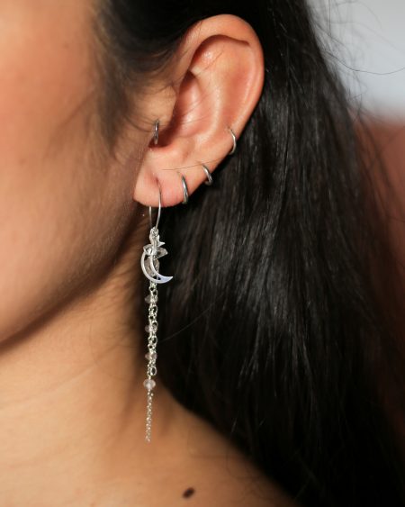 het model draagt 'Moon Party' lange zilveren oorhangers met edelstenen en een zilveren maanhanger