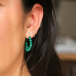Het model draagt oorringen met groene Malachiet edelsteen brokjes . De oorringen sluiten met een zilveren steker door het oor.