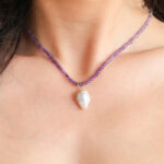 het model draagt een edelsteen ketting van amethist en maansteen. De hanger is een grote Zuid Zee keshi parel