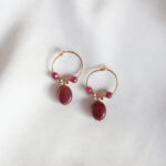 korte goldfilled oorringen met een ovale rode robijn in het midden en twee rode robijntjes aan weerszijden.