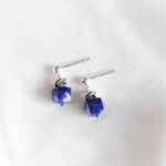 korte zilveren oorhanger met een koningsblauwe lapis lazuli kubus en een gedraaide zilveren ring bovenop. De facet geslepen lapis edelsteen heeft pyriet insluitsels